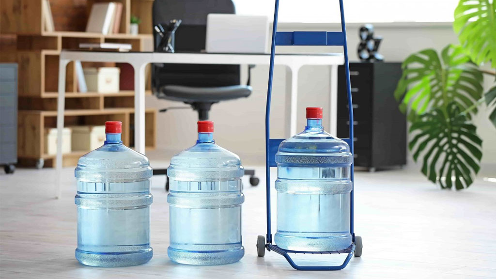 Responsable vérifiant le stock de bonbonnes d'eau dans une cuisine d'entreprise