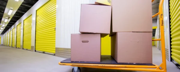 Un homme charge des meubles dans un box de stockage ouvert devant une maison pendant un déménagement.