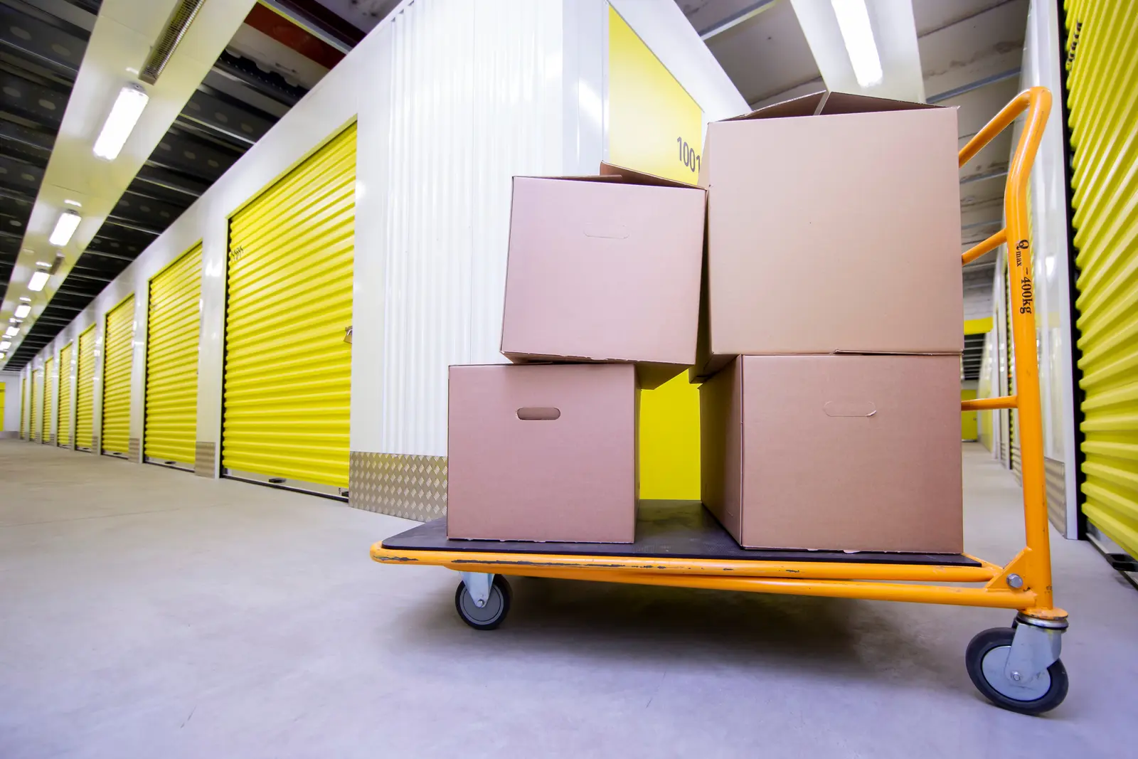Un homme charge des meubles dans un box de stockage ouvert devant une maison pendant un déménagement.
